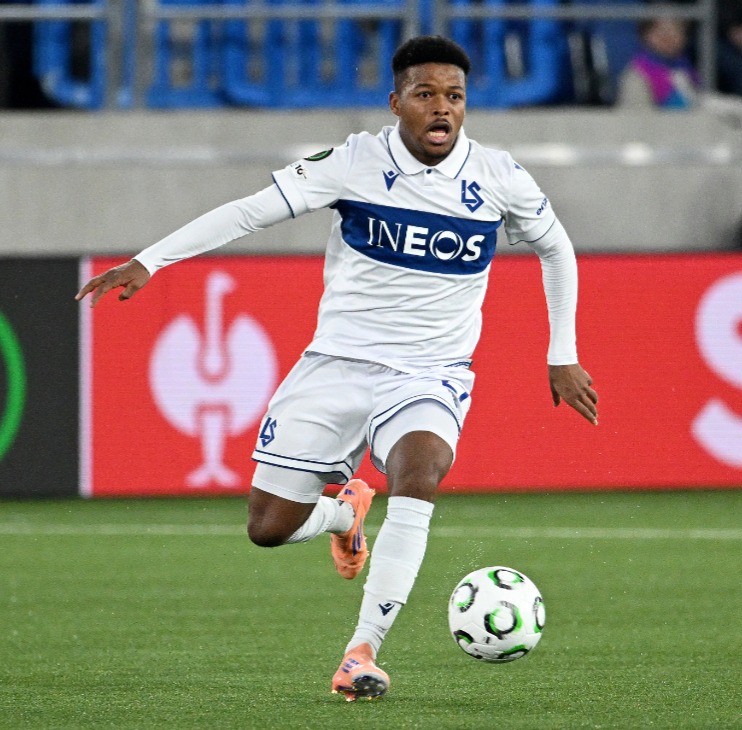 Fussballer läuft Ball auf Feld hinterher.