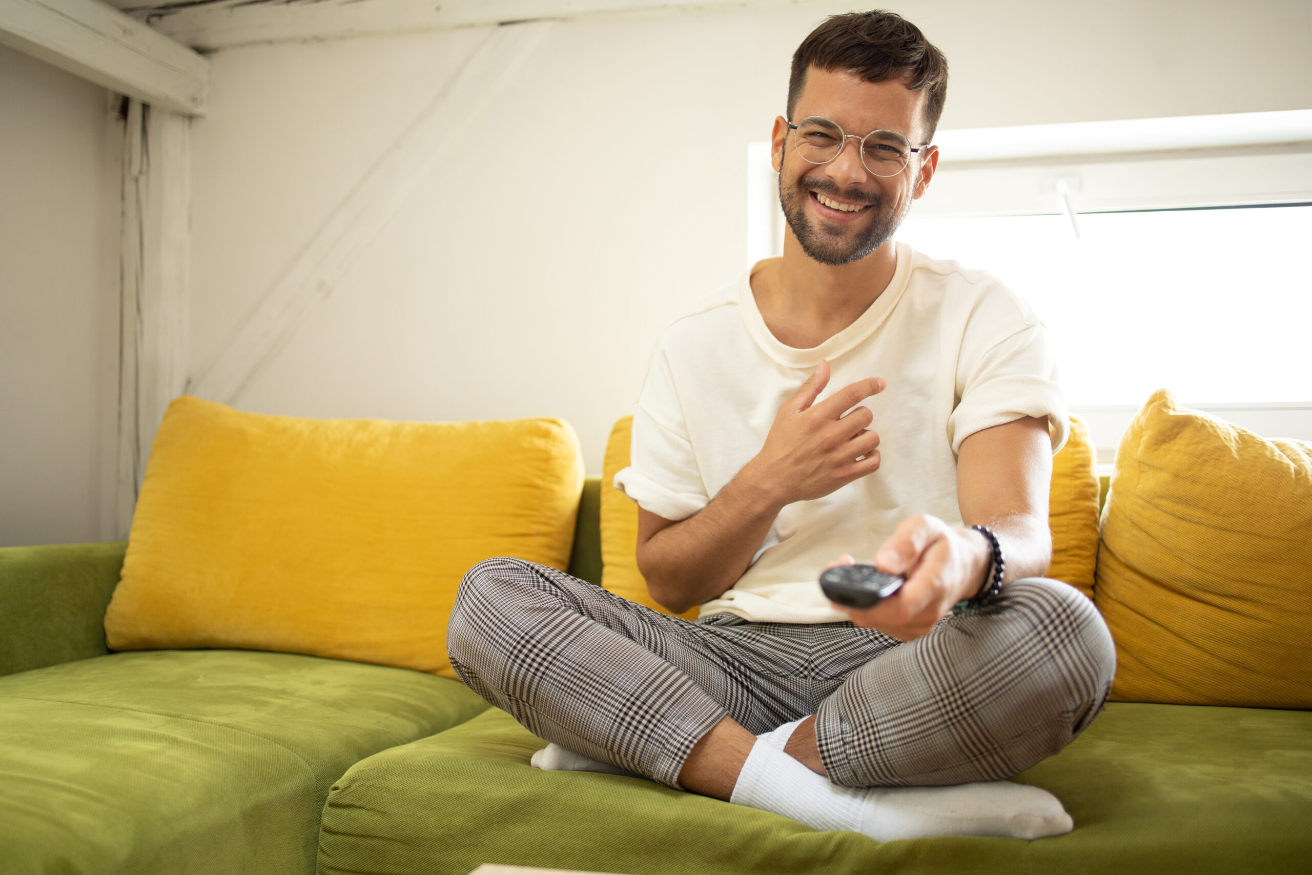 Mann, der zu Hause seine Lieblingsfernsehsendung genießt Junger Mann, der zu Hause fernsieht und sich amüsiert