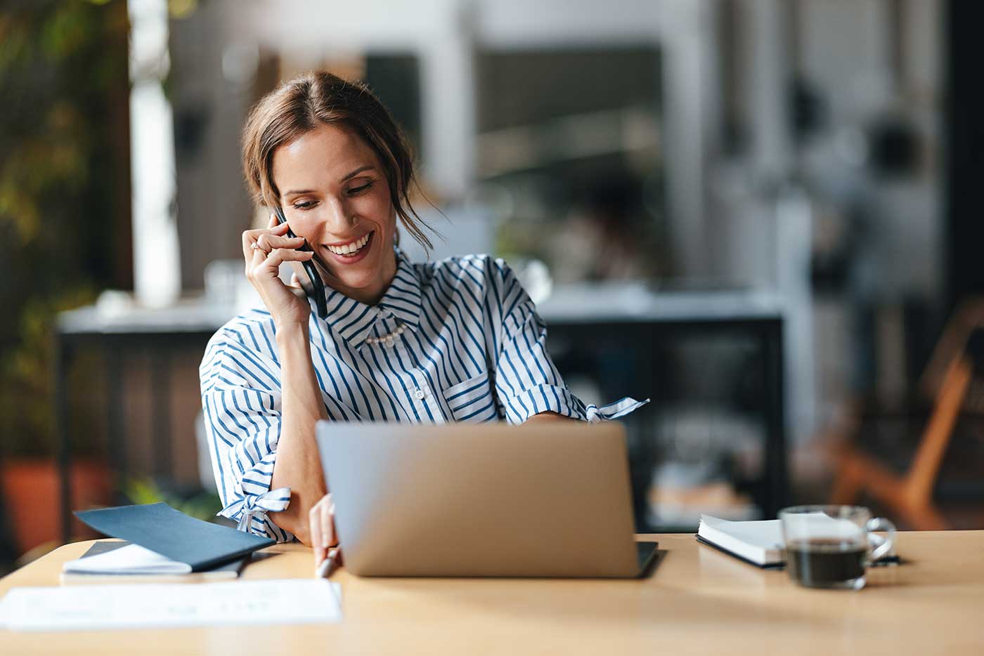 kontaktiere-uns-3 Frau mit Phone am Ohr vor Laptop.