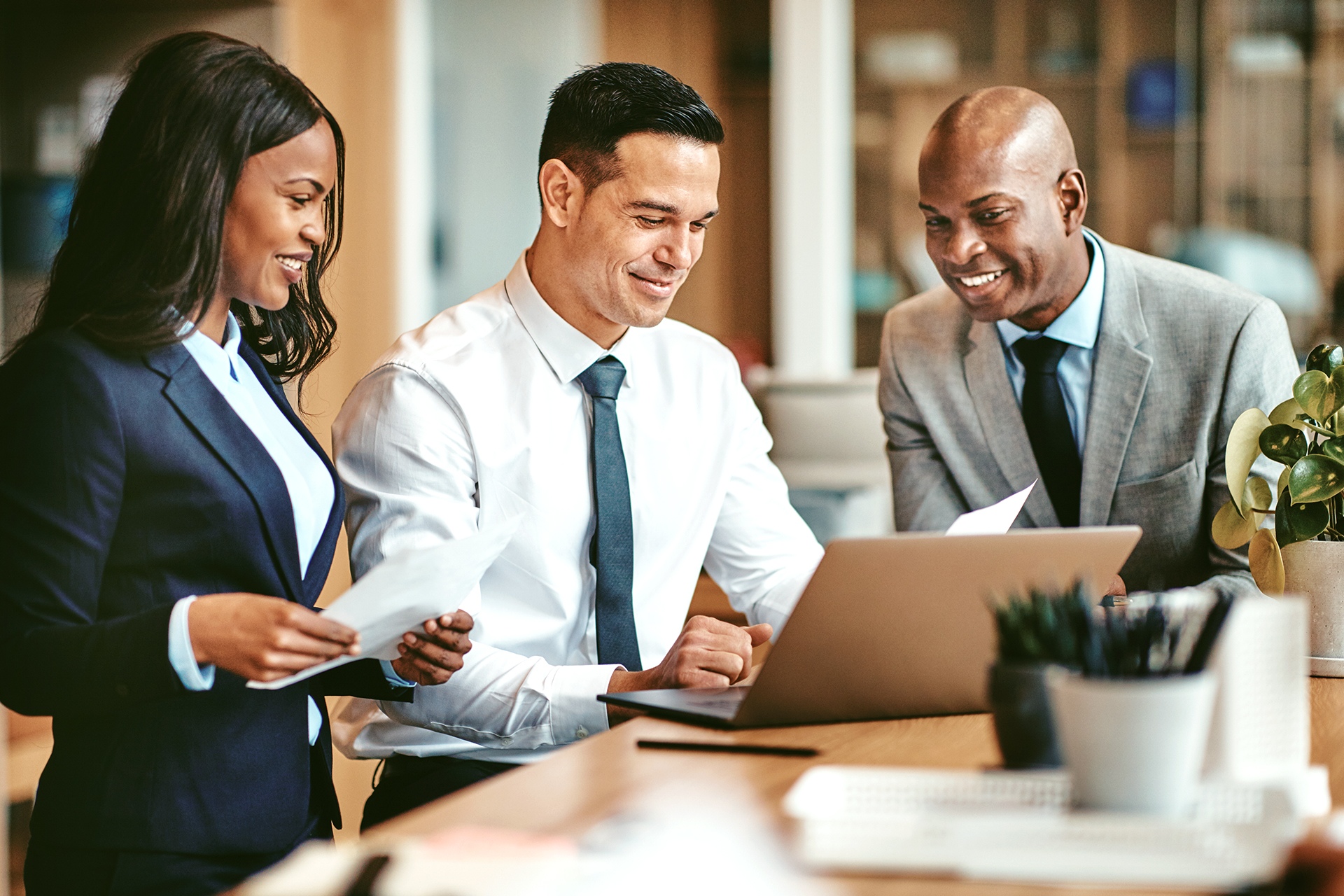 Smiling,Group,Of,Diverse,Businesspeople,Going,Over,Paperwork,Together,And