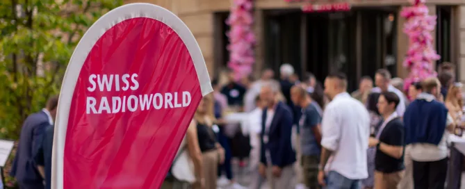 Radio Night Swiss Radioworld Logo im Vordergrund, Party im Hintergrund