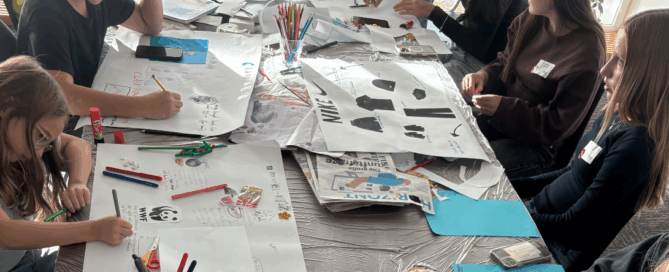 Kinder sitzen um einen Tisch malen und basteln.