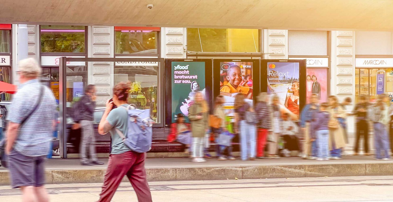 Tramhaltestelle mit DOOH-Werbung und vielen wartenden Menschen