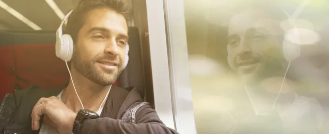 Man sitzt im Zug und hört Audio