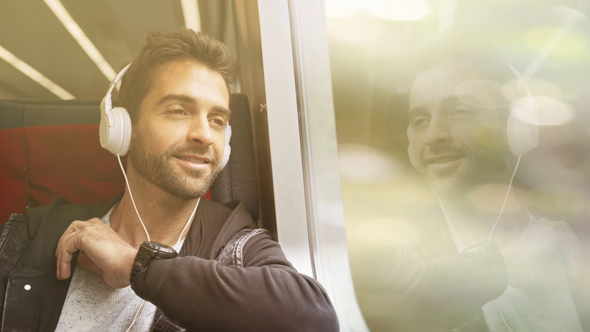 Man sitzt im Zug und hört Audio