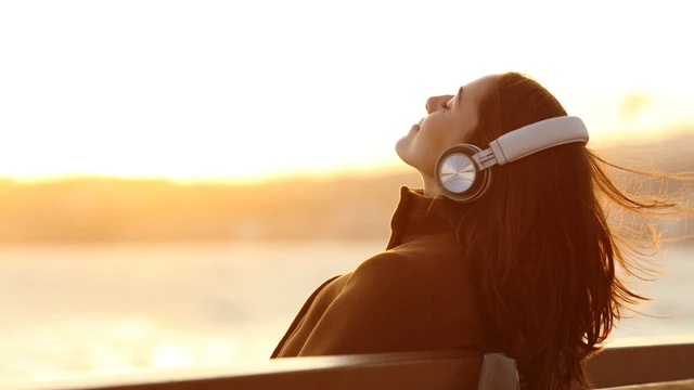 Woman on the beach enjoys audio through her headphones