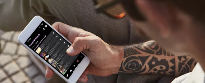 Mann sitzt mit Handy und schaut sich Audio-Platform an